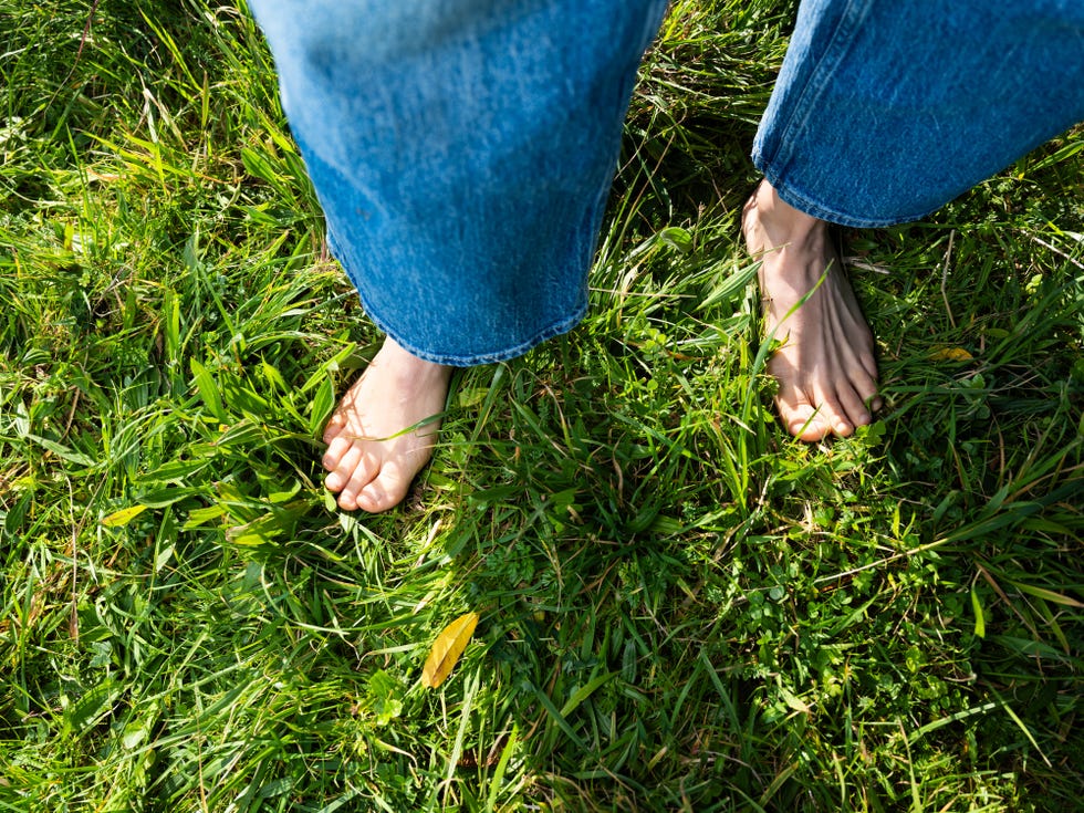 Person walking barefoot in green grass field person standing barefoot on lush green grass, feeling connected to nature
