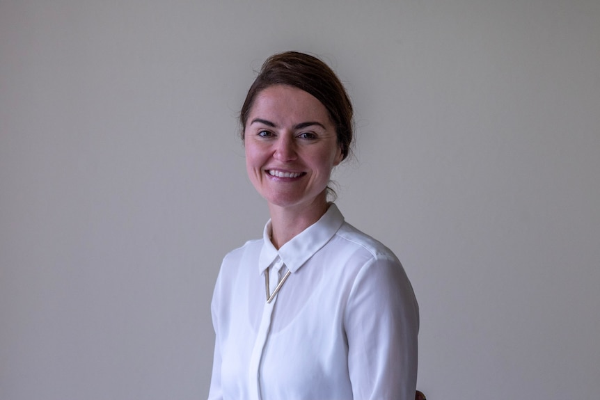 headshot of sarah trobe, smiling wearing a white shirt and her hair tied back.