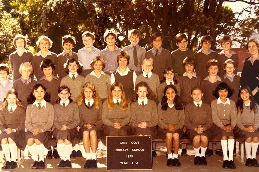 Year 6 students in uniform including a young Nicole Kidman with hands clasped and long wavy hair in school photo