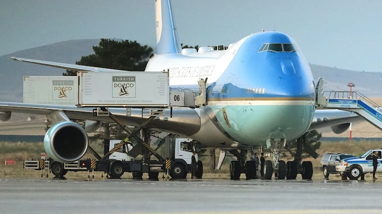 Catering trucks are parked at Air Force One on the tarmac as the motorcade carrying US President Donald Trump arrives on the tarmac to depart following the NATO summit at Ankara International Airport in Ankara.