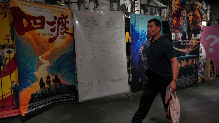 Slide 1 of 2 Previous Next A man walks by a drawing poster promoting a Chinese animated film "Niulai" on display with other movie posters at a cinema in Beijing, Tuesday, Aug. 18, 2026.