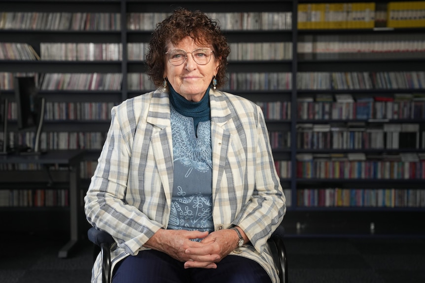 She sits in a room with CDs and videos behind her