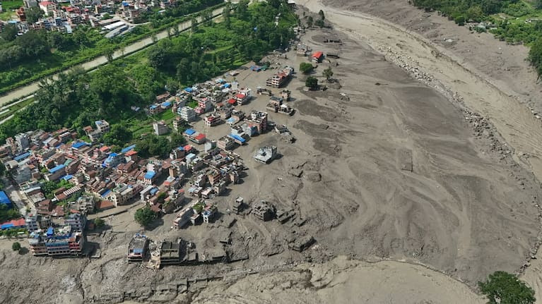 Damaged houses stand precariously near the swollen, debris-choked banks of the Trishuli River after flash floods in Nepal's Nuwakot district