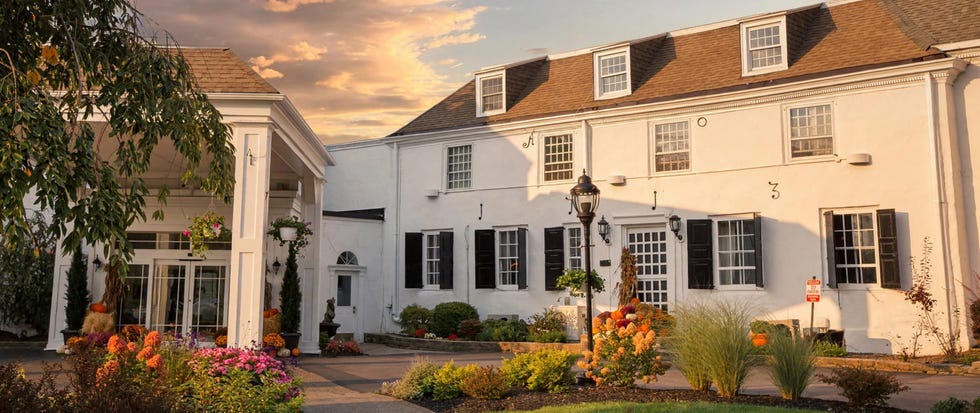 Historic building with flower garden and decorative lamp under a sunset sky.