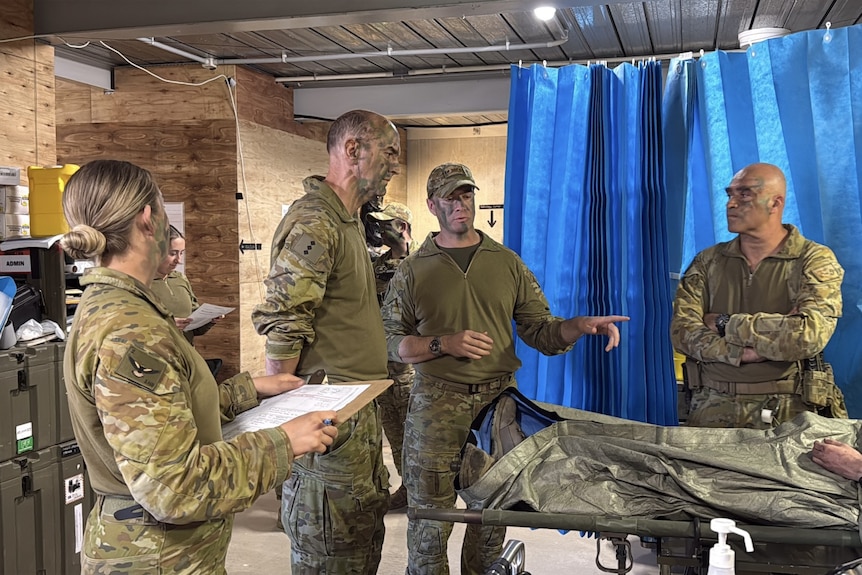 Four military personnel stand in a room together