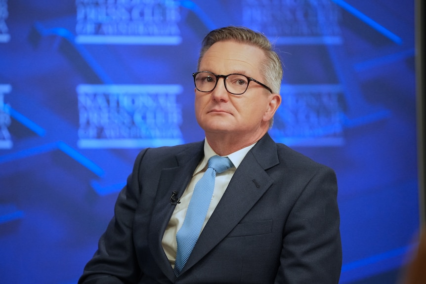 A mid-shot of Chris Bowen, a man in a navy suit