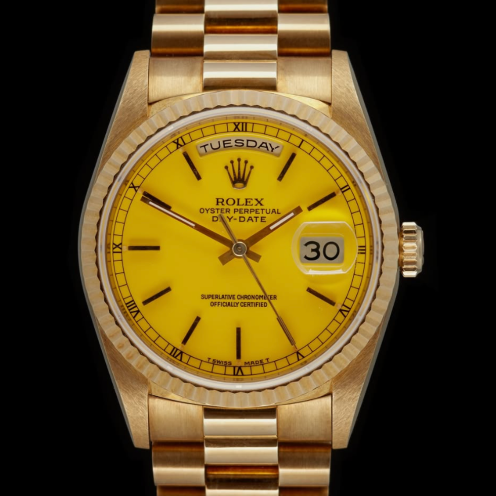 gold wristwatch with yellow dial showing tuesday, date 30.