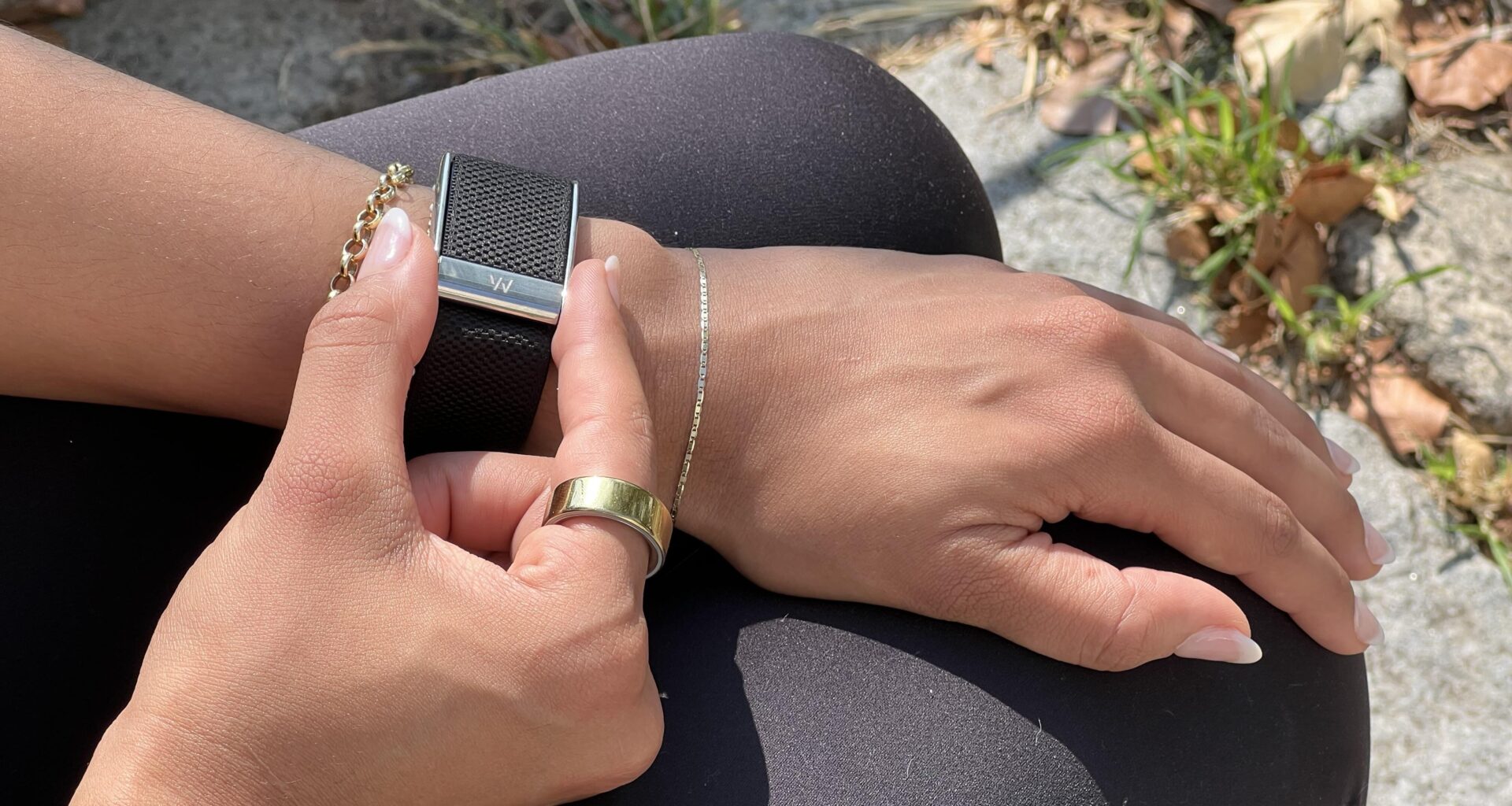 A Whoop 5.0 on a wrist fingers grasping the side indents to get an ECG reading.