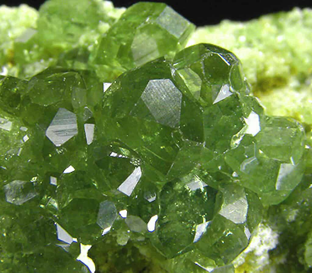Close-up of bright green crystalline mineral structure with sharp edges.