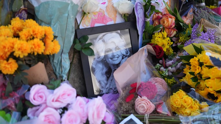 Images and flowers form a makeshift memorial honoring Dolly Parton in front of her statue in Sevierville, Tennessee, Tuesday, August 25, 2026.