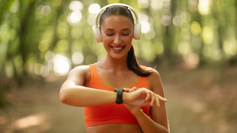 Woman on a run, checking a smartwatch on her wrist.
