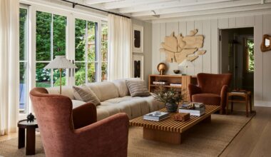 Living room with white panelled walls, wood floor, rust armchairs, cream sofa, striped marquetry coffee table