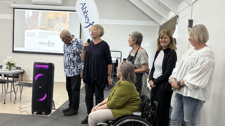 Lucy Miller speaks at a fundraising breakfast accompanied by volunteer committee members.