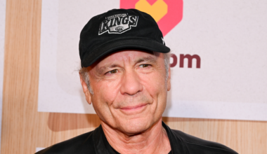 Bruce Dickinson smiling in a black baseball cap