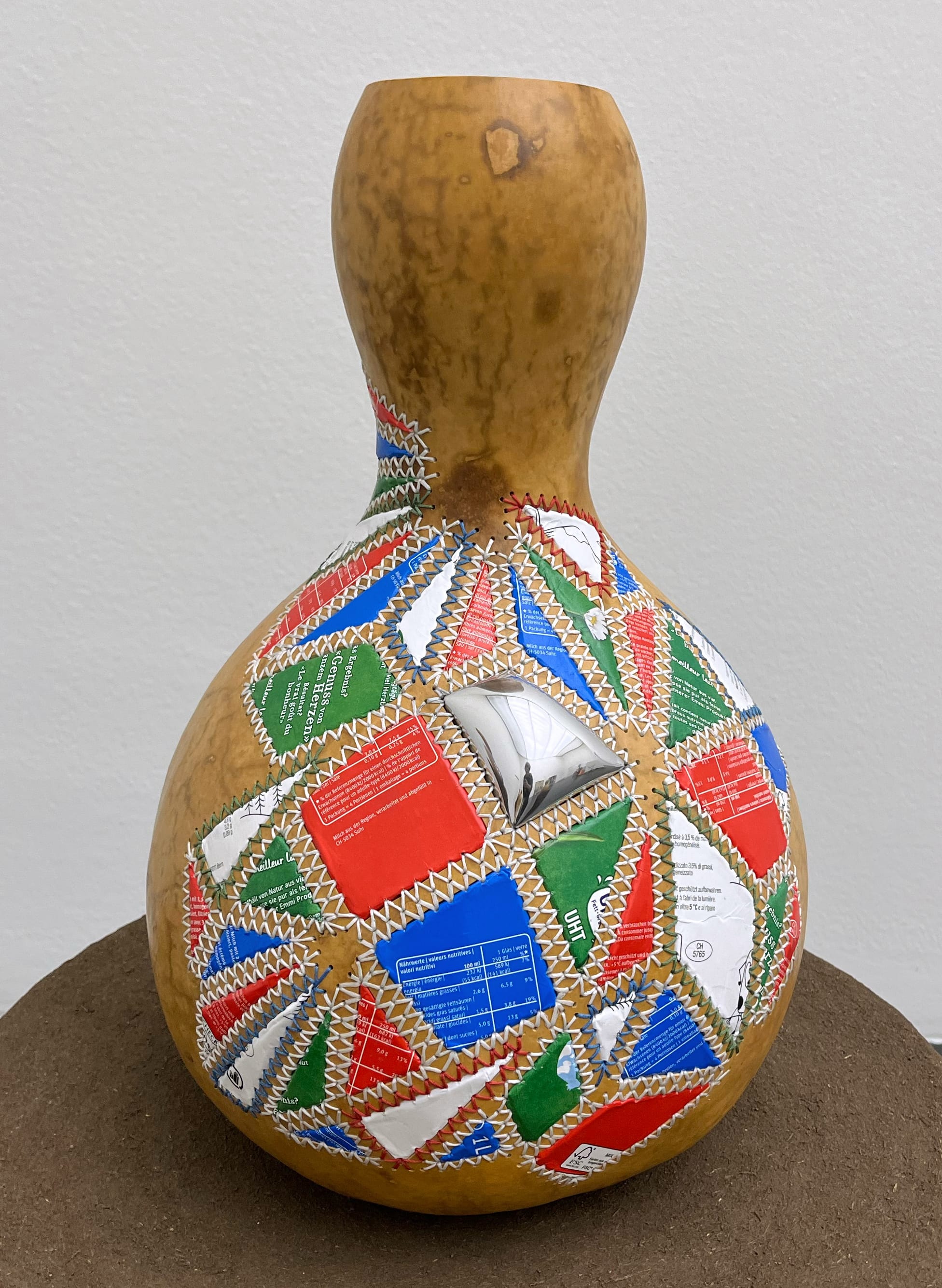a gourd with colorful aluminum patches sewn on the side