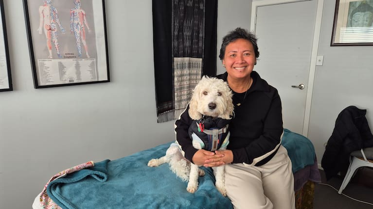 Miria with her spoodle Sydney in the studio of her business, Empowering Wellness, in Milford, Auckland. 