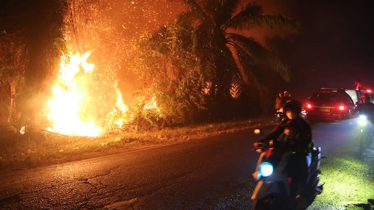 Motorists ride past a wildfire burning through a peatland field in Sampit, Central Kalimantan, Indonesia.