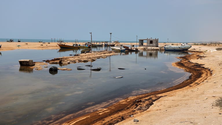 Oil residue lines the shore near fishing boats on Qeshm Island, Iran, Thursday, August 13, 2026.