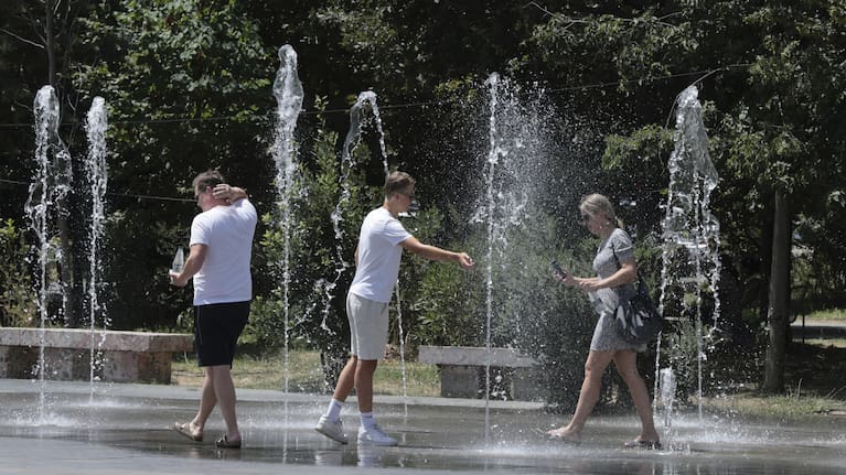 Pedestrians cool themselves in a fountain in central Tirana, Albania, during a heatwave, July 25, 2025,