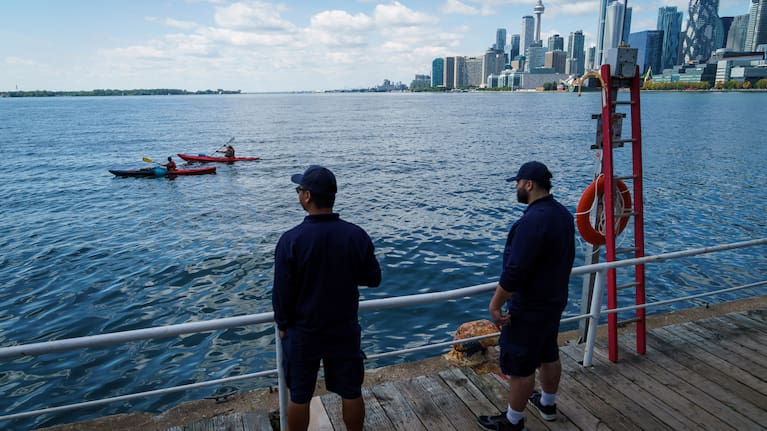 People look out across Lake Ontario from the harbor in Toronto