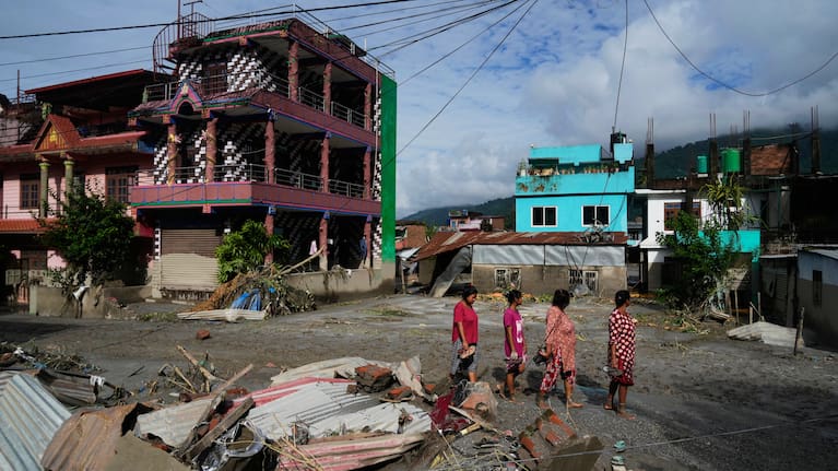 People walk past damage in the aftermath of flash floods in Devighat in the Nuwakot district in Nepal, Thursday, August 27, 2026.