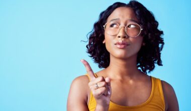 Confused woman, thinking bubble and studio mockup background. Pensive, annoyed or curious person contemplating decision. Girl with solution or idea pointing for marketing advertisement.