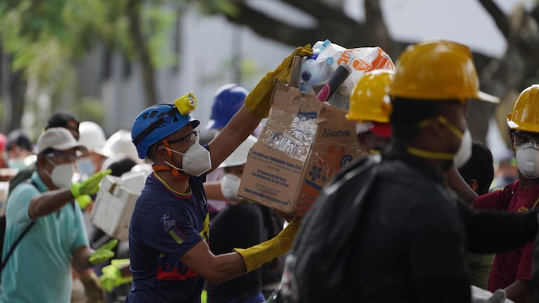 Rescuers pass food packages for rescue teams and volunteers searching through the rubble four days after an earthquake hit Cali, Colombia, Friday, August 14, 2026.