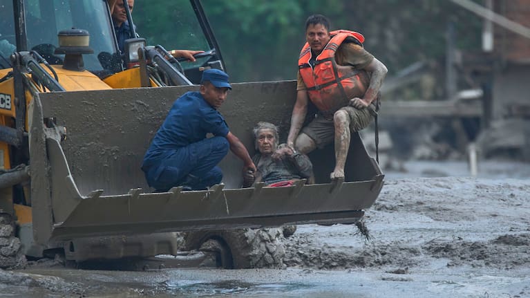 Rescuers use an earthmover to carry a victim of flash flooding to safety along the Trishuli River in Nepal's Nuwakot district.