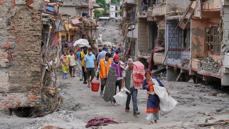 Residents carry their belongings salvaged from their damaged homes filled with mud and debris in Devighat, in Nepal's Nuwakot district, Saturday, August 29, 2026, following the August 26 flash floods.