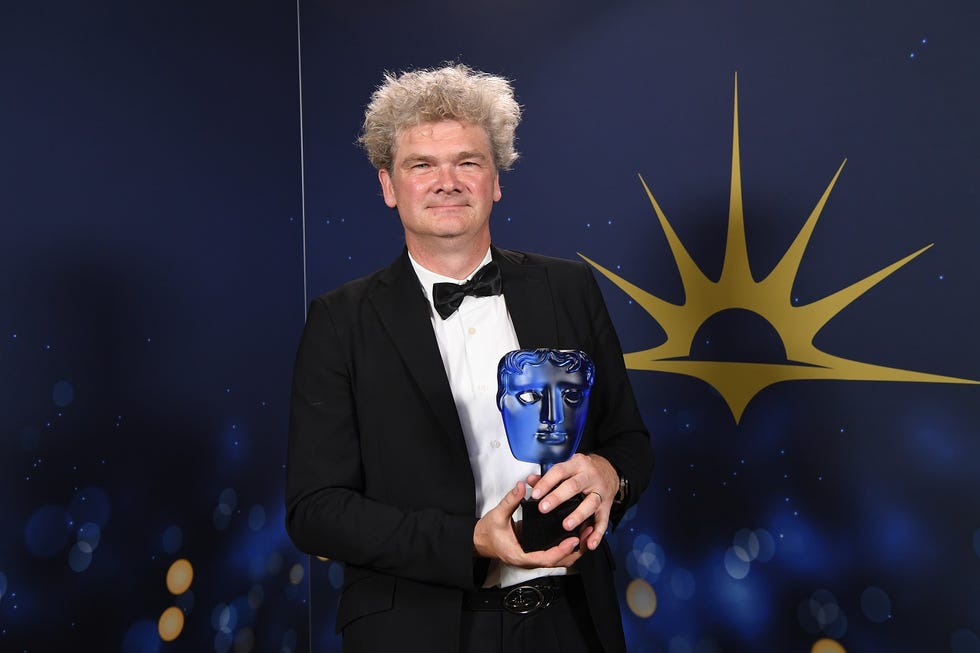 Simon Farnaby at the 2023 BAFTA Television Awards simon farnaby at the 2023 bafta television awards, simon is looking at the camera while wearing a tuxedo and holding a blue bafta award