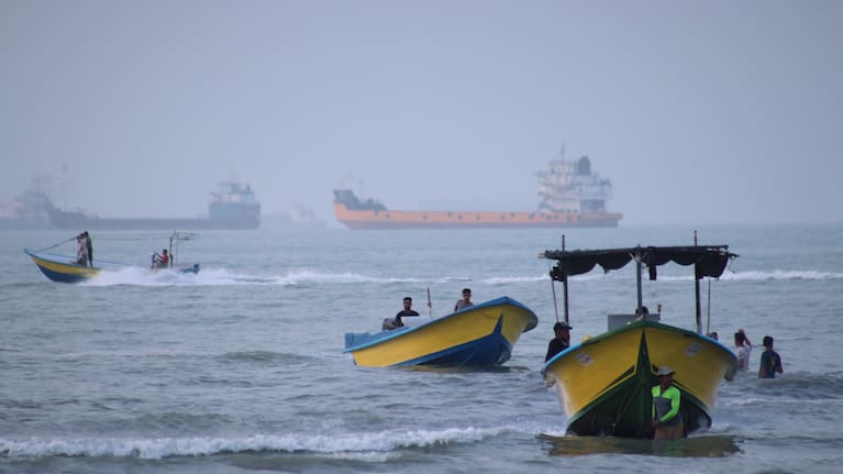 Small boats line the shore as cargo ships and other commercial vessels appear anchored in the Strait of Hormuz off Bandar Abbas, Iran.