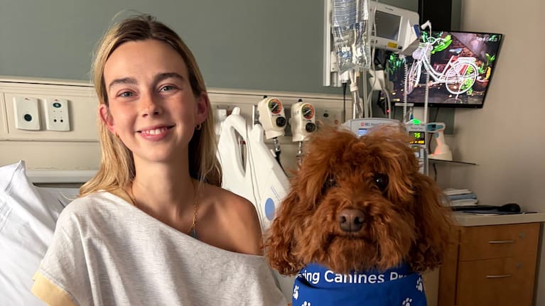 Towle poses for a photo with a dog in hospital.