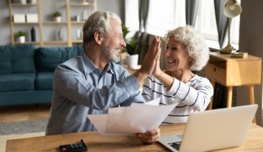A retired couple is high-fiving one another.