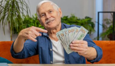 A retired investor is holding several $100 bills, fanned out in his hand.