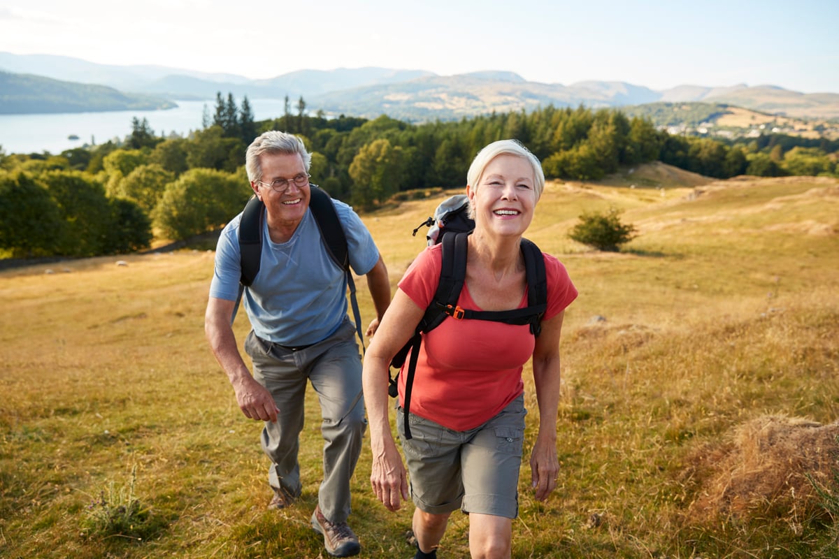 Two people hiking outside with backpacks on.