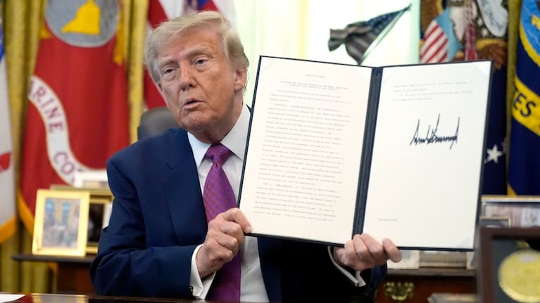 US President Donald Trump holds up a signed executive order in the Oval Office of the White House.