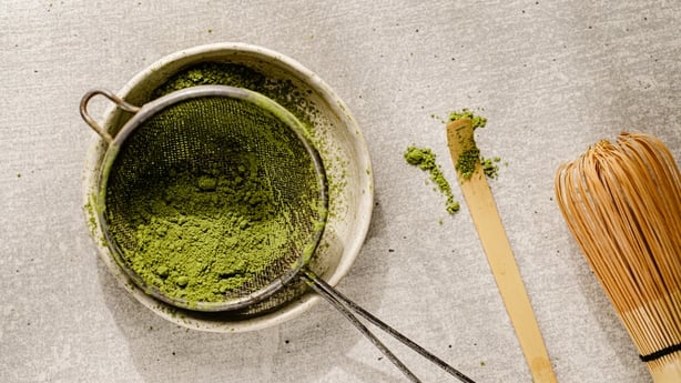 Top view of matcha powder in a colander over kitchen table. Prepaing matcha latte at home.
