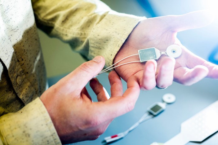Close-up of Sherman attaching a small sensor to a participant's palm and fingers.