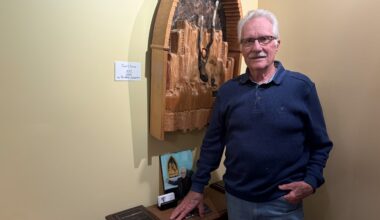 Man standing in his home studio with one of his sculptures in the background