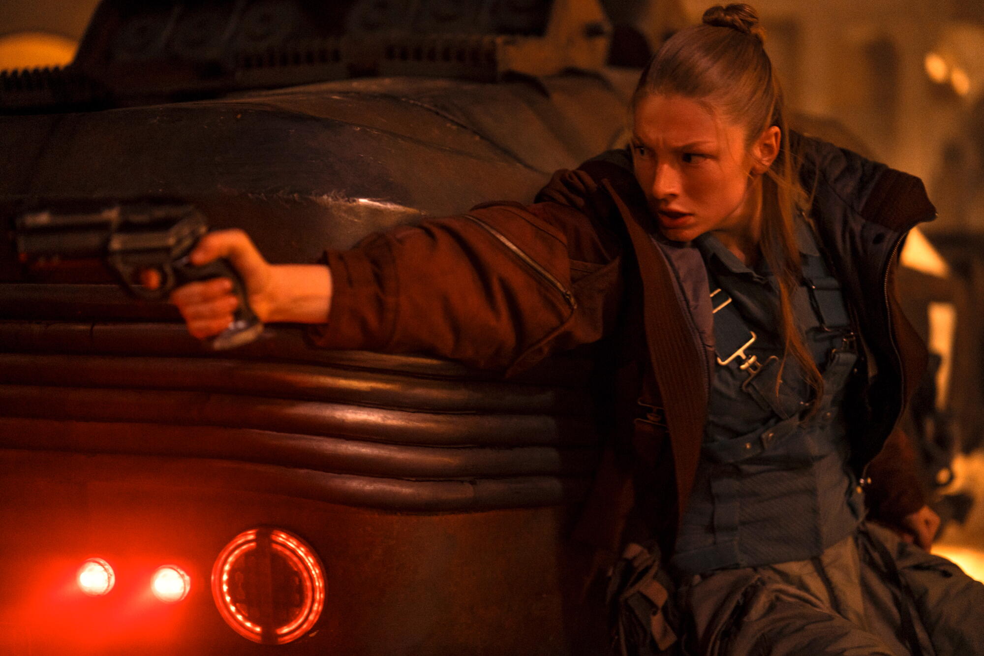 A woman with her arm outstretched with a gun in her hand.