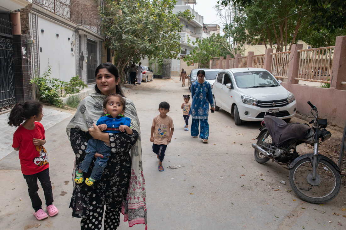 Umaima Ansari, whose 3-year-old son Hussain tested positive for HIV after an operation to address complications related to hydrocephalus, walks near her home with her children on July 26, 2026 in Hyderabad, Pakistan. Ansari says multiple healthcare providers refused her son, who also has cerebral palsy, care after learning about his HIV diagnosis.