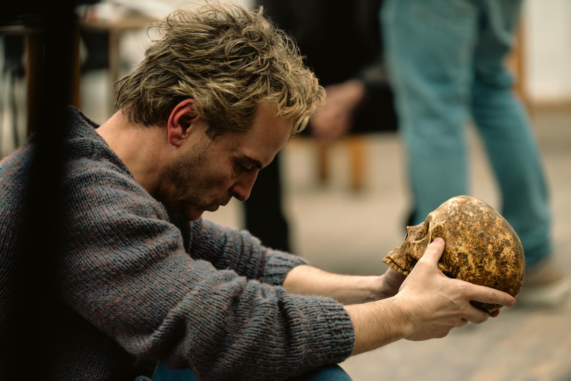 A man sits deep in thought, holding a skull.