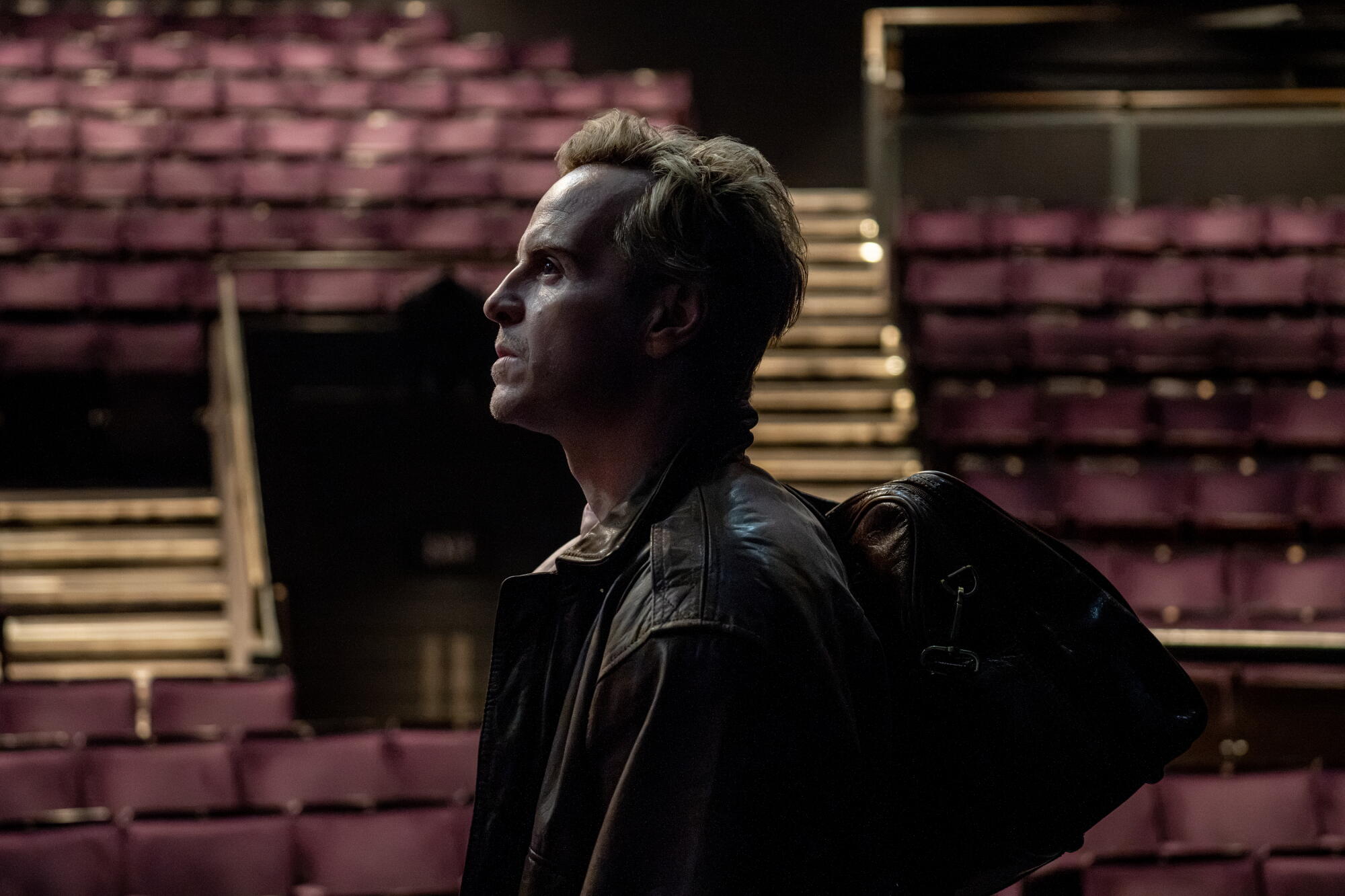 An actor steps onto a darkened stage.