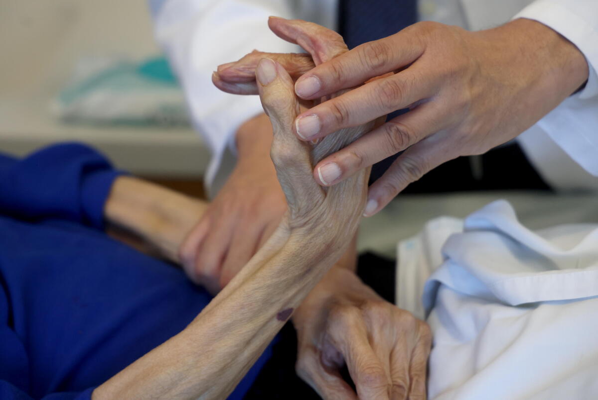 Dr. Zaldy Tan examines the hands of Jessie, 84, who suffers from vascular dementia.