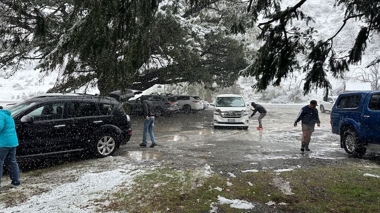 Cars pictured in the snow, and putting on chains on Porters Pass.