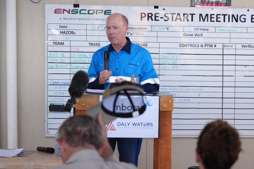 A man in a high-vis work shirt speaking into a microphone as he addresses the crowd.