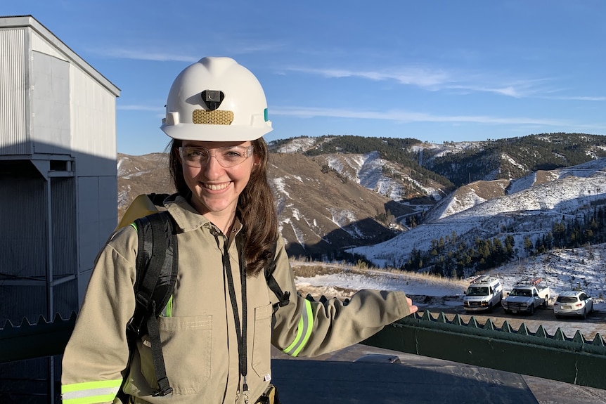 A woman in a hard hat with a snowy mountain in the background
