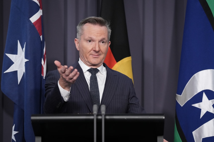 A man in a suit stands at a lectern