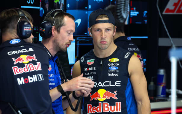 Liam Lawson listens to a Red Bull team member.