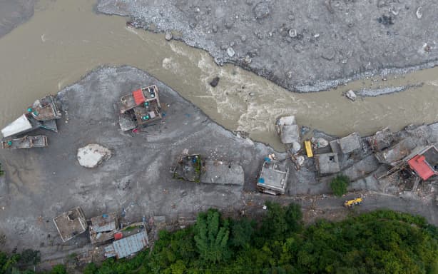 An aerial view shows a torrent of muddy water surging past houses and through the Trishuli river in the aftermath of flash floods, at Betrawati in Nepal's Nuwakot district on August 29, 2026. More than 3,000 people were listed as missing on August 30, with another 768 confirmed dead, after the flash floods and landslides that hit the Nepal-Tibet border. (Photo by PRABIN RANABHAT / AFP)